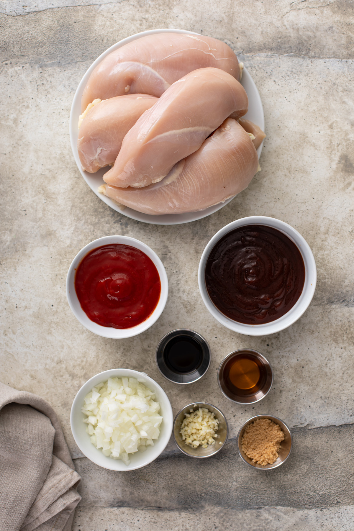 Ingredients for slow cooker pulled chicken arranged on a countertop.