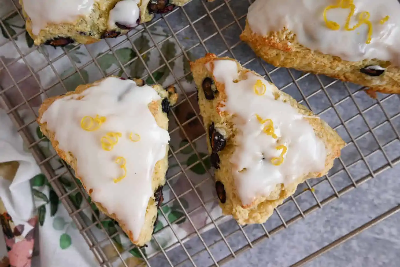 Glazed blueberry lemon scones set on a wire cooling rack.