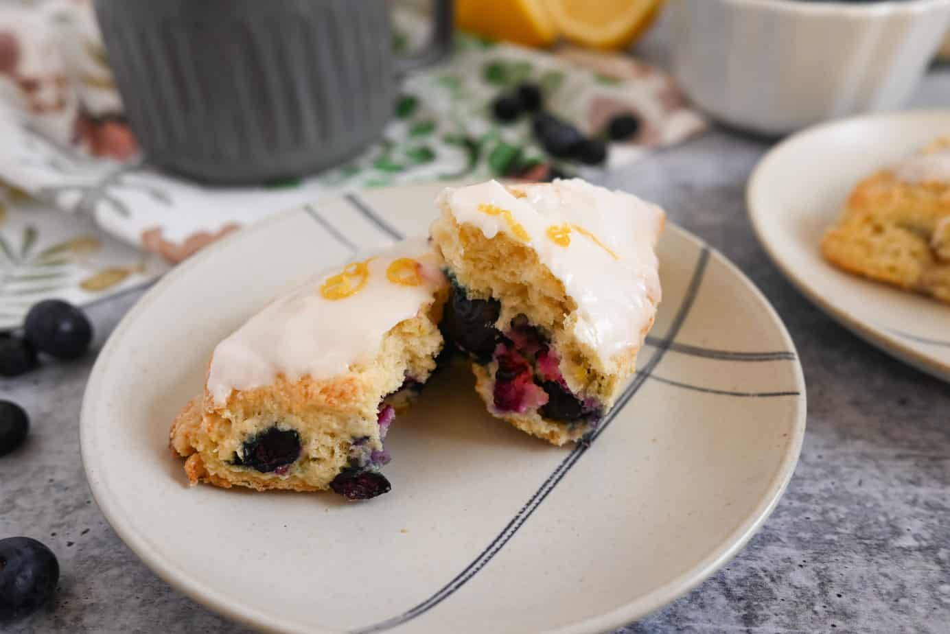 Blueberry lemon scone broken in half and set on a cream and blue plate.