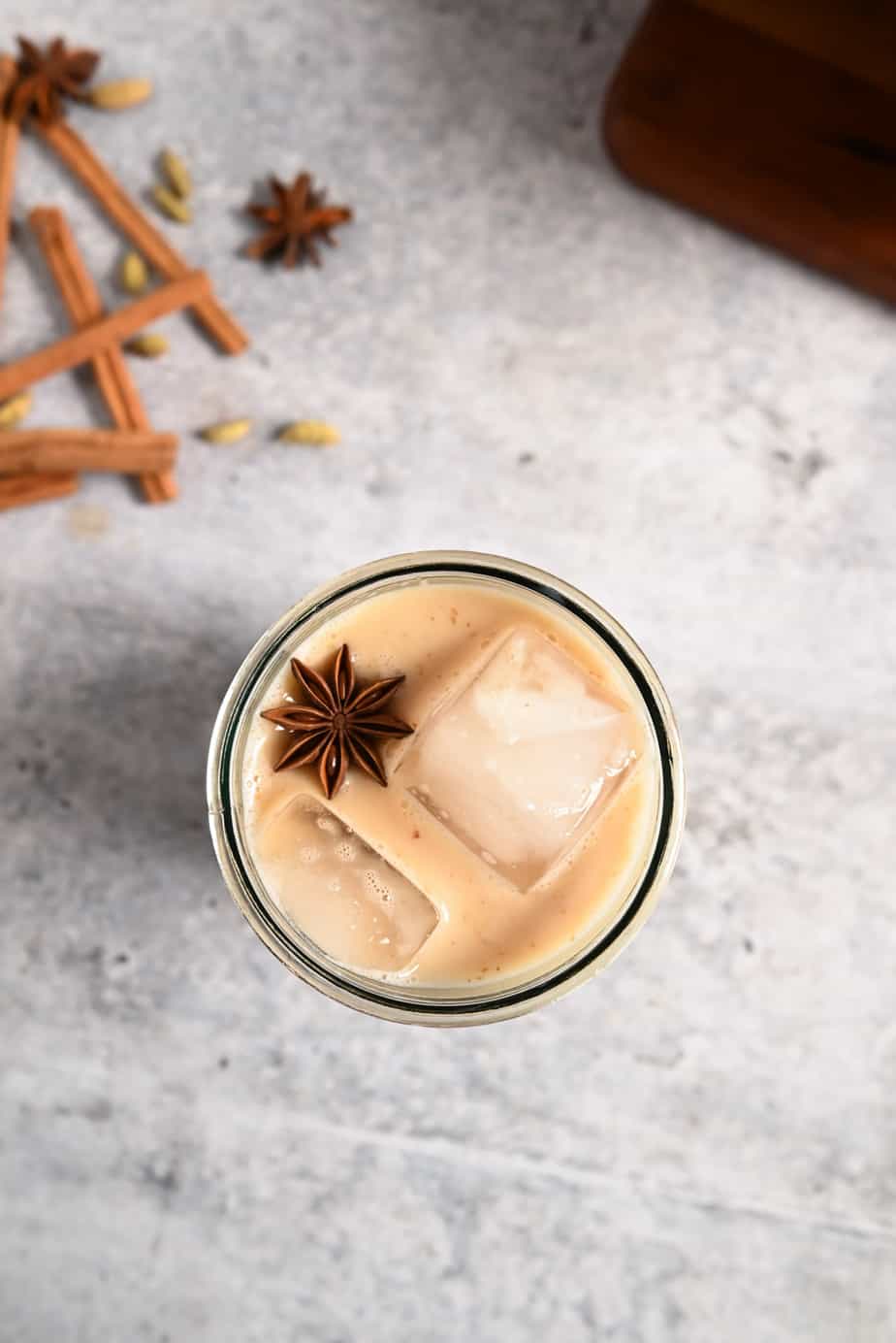 Overhead view of a glass of iced chai garnished with a star anise pod
