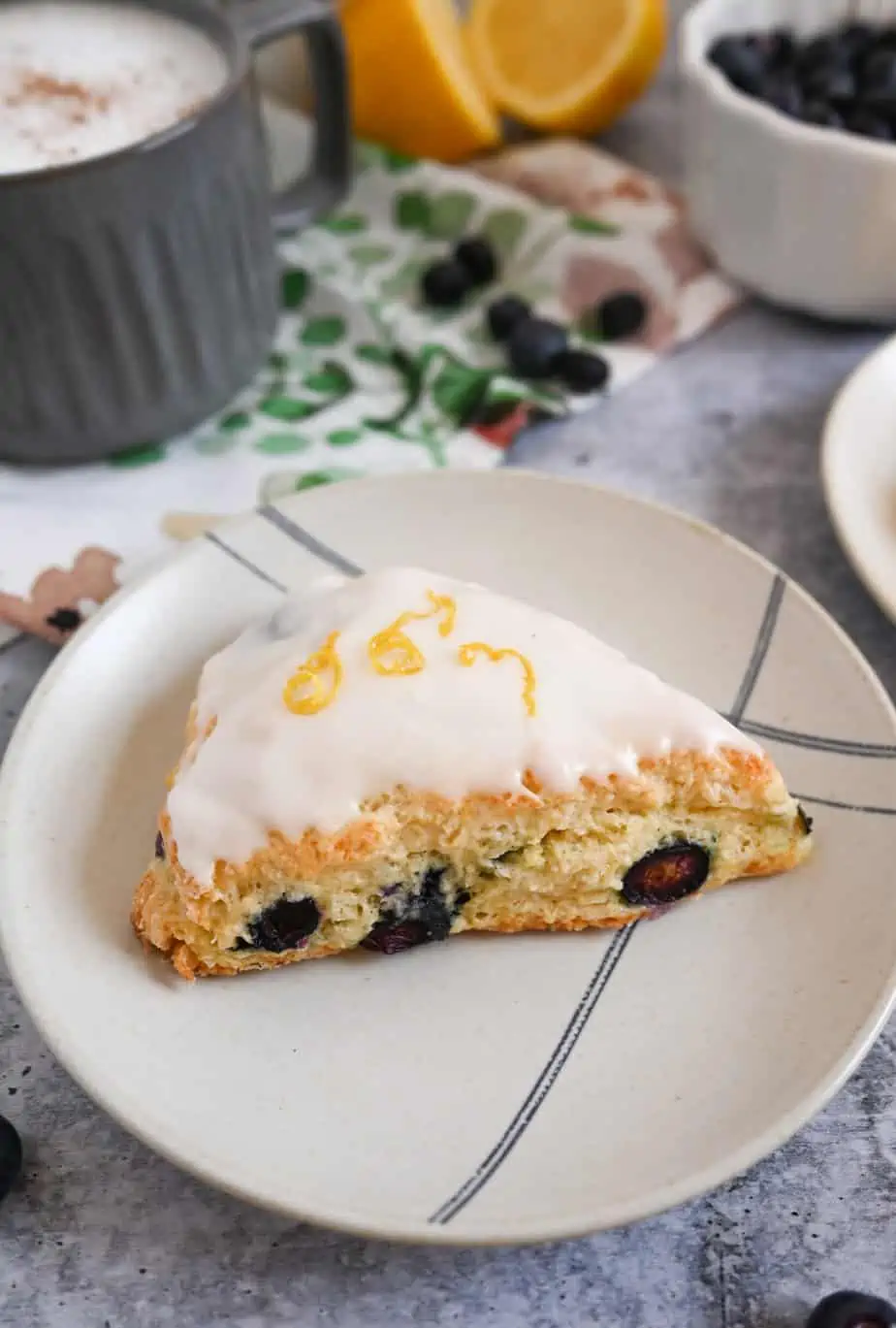 Glazed blueberry lemon scone set on a cream and blue plate.