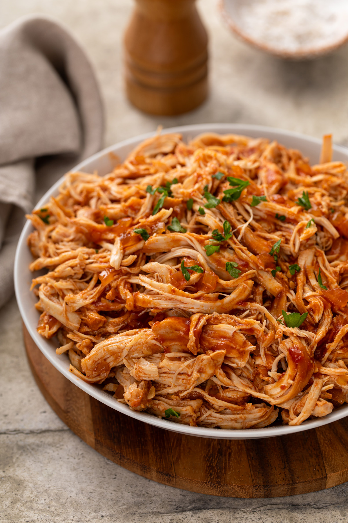 Large white serving bowl filled with shredded BBQ chicken.