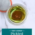 Overhead view of an open jar of pickled garlic scapes. Text overlay includes recipe name.