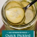 Fork lifting slices of pickled cucumbers from a glass jar. Text overlay includes recipe name.