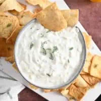 Overhead view of two pita chips tucked into a bowl of homemade tzatziki.