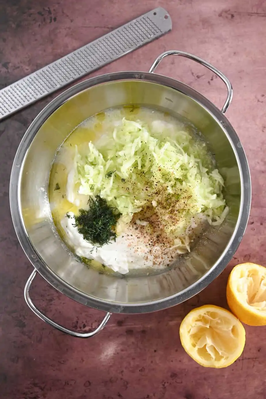 Ingredients for homemade tzatziki in a metal mixing bowl, ready to be stirred together.