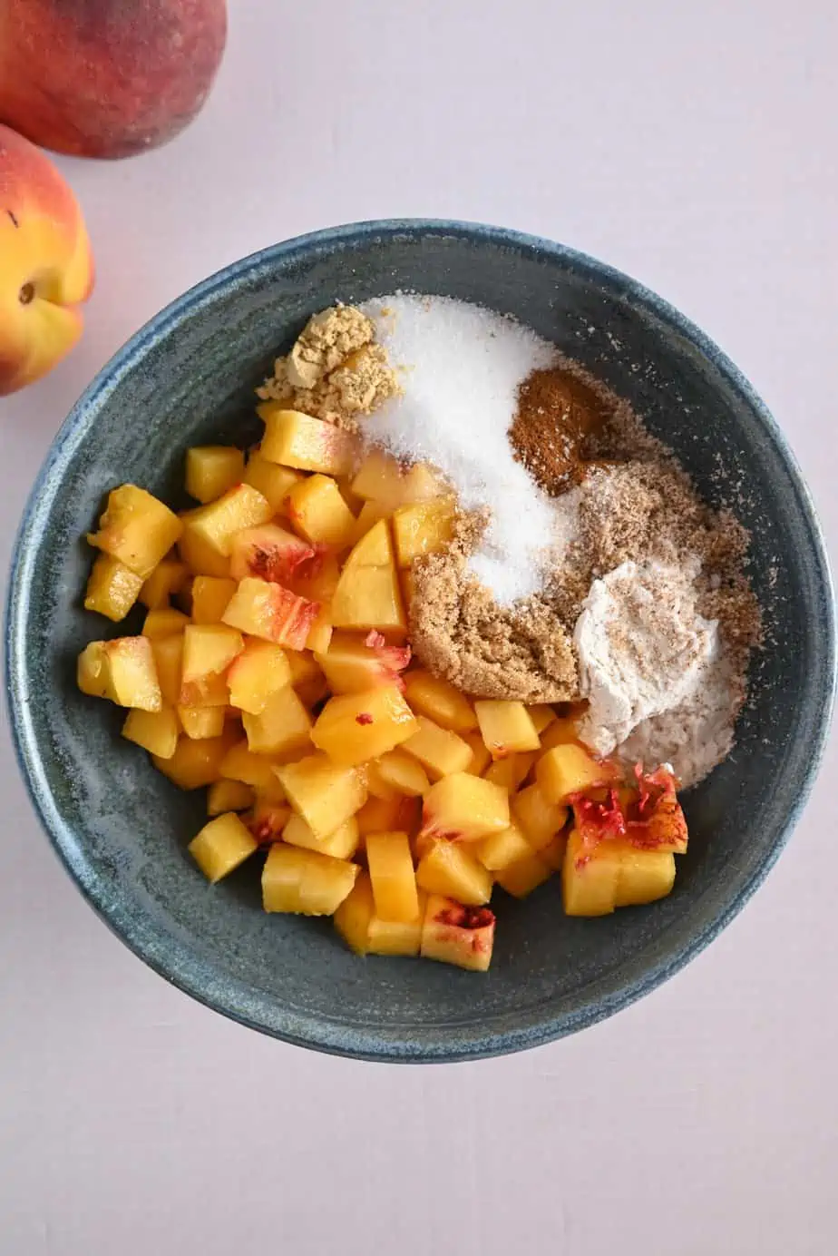 Ingredients for peach hand pie filling in a blue pottery bowl.