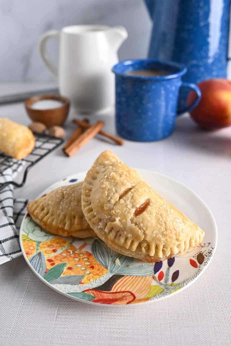 Two peach hand pies perched on a colorful plate.