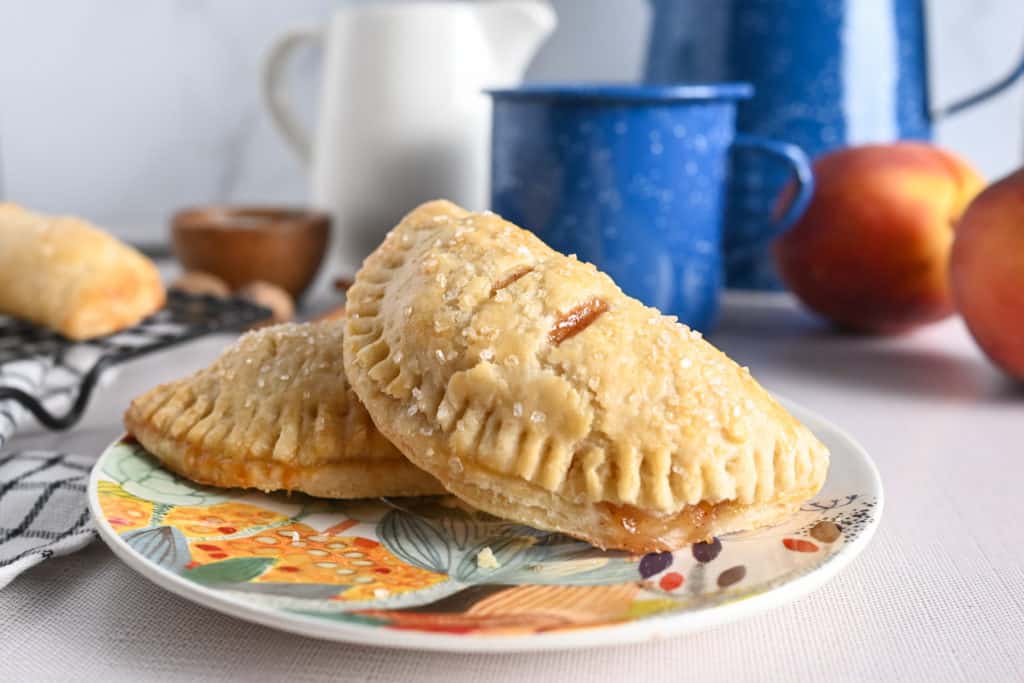 Close up of two peach hand pies arranged on a colored plate.