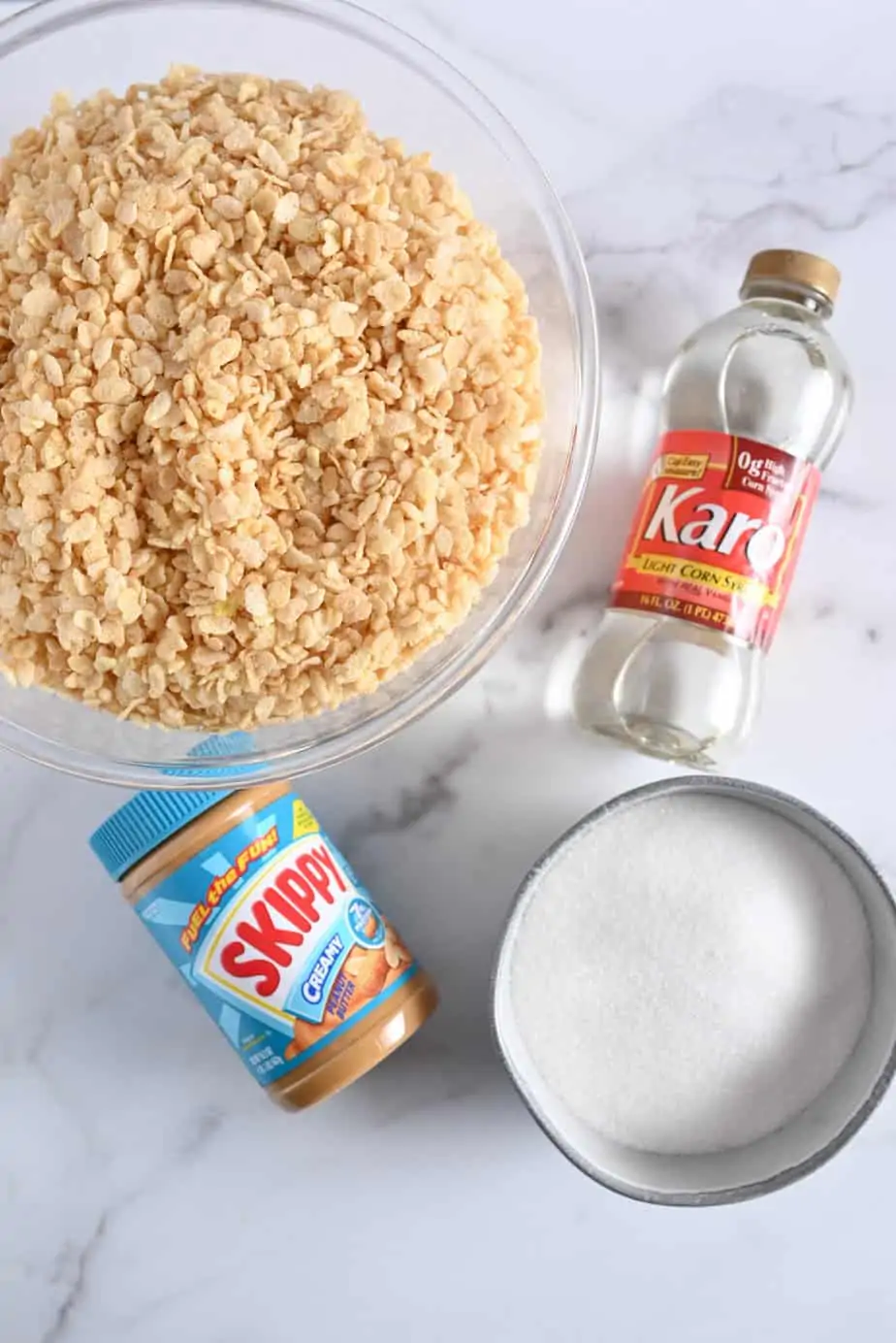 Ingredients for peanut butter rice krispie bars arranged on a marble countertop.
