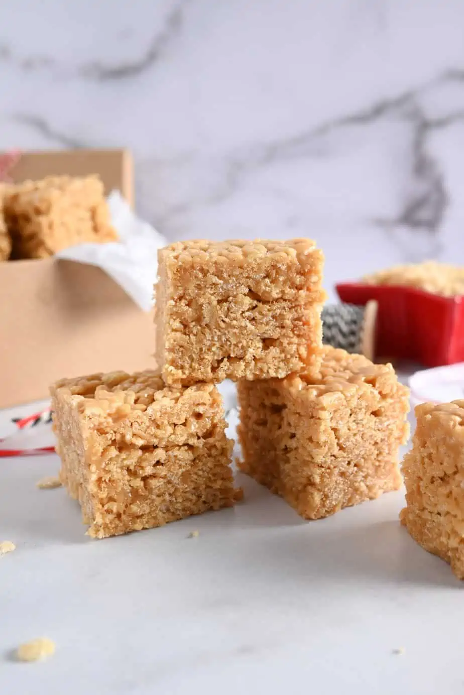 Three stacked peanut butter rice krispie bars on a marble countertop, with a box of bars in the background.