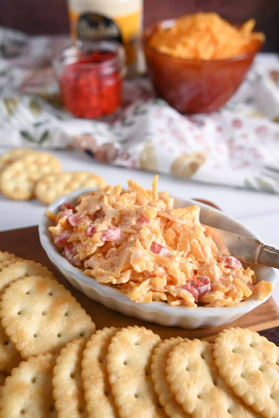 White dish filled with pimento cheese on a cutting board with butter crackers.