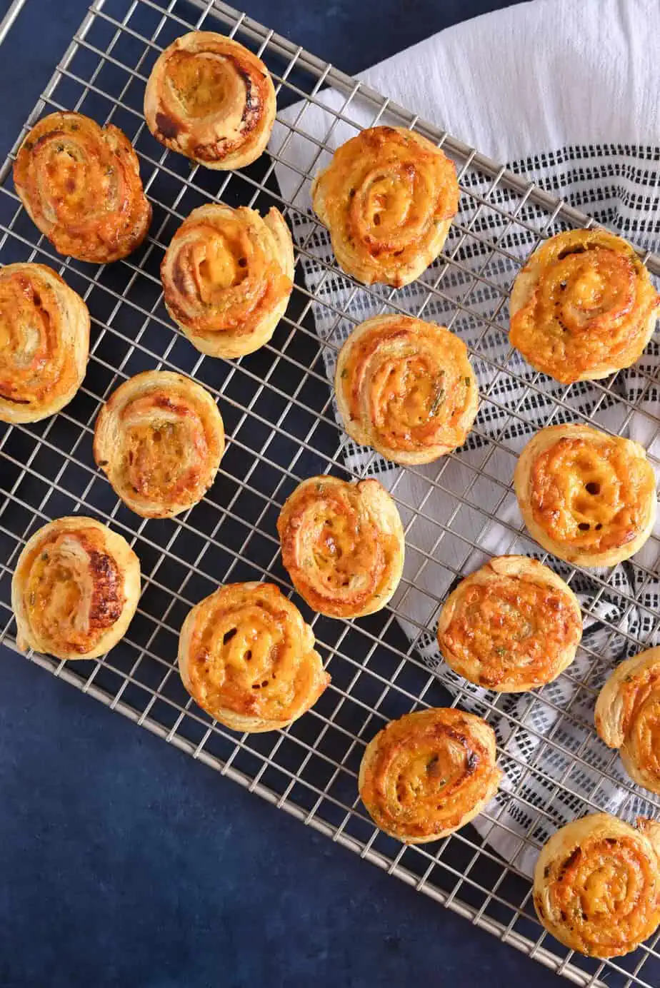 Hot ham and cheese pinwheels cooling on a wire rack.