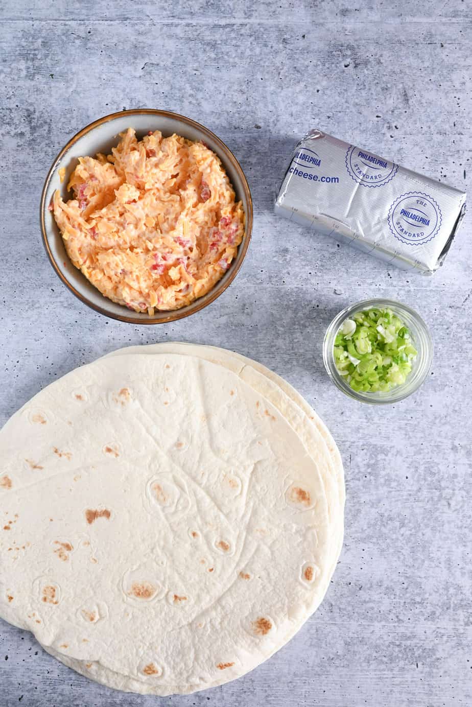 Pimento cheese pinwheel ingredients on a stone countertop.