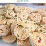 Platter of pimento cheese pinwheels with toothpicks in two of the pinwheels, ready to be taken. Text overlay includes recipe name.