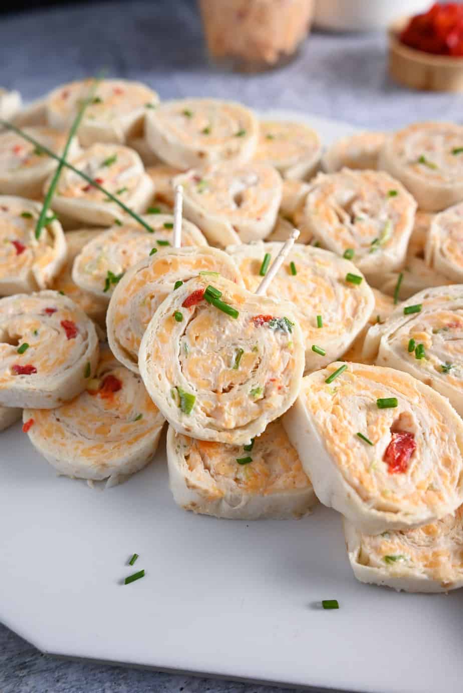 Platter of pimento cheese pinwheels with toothpicks in two of the pinwheels, ready to be taken.