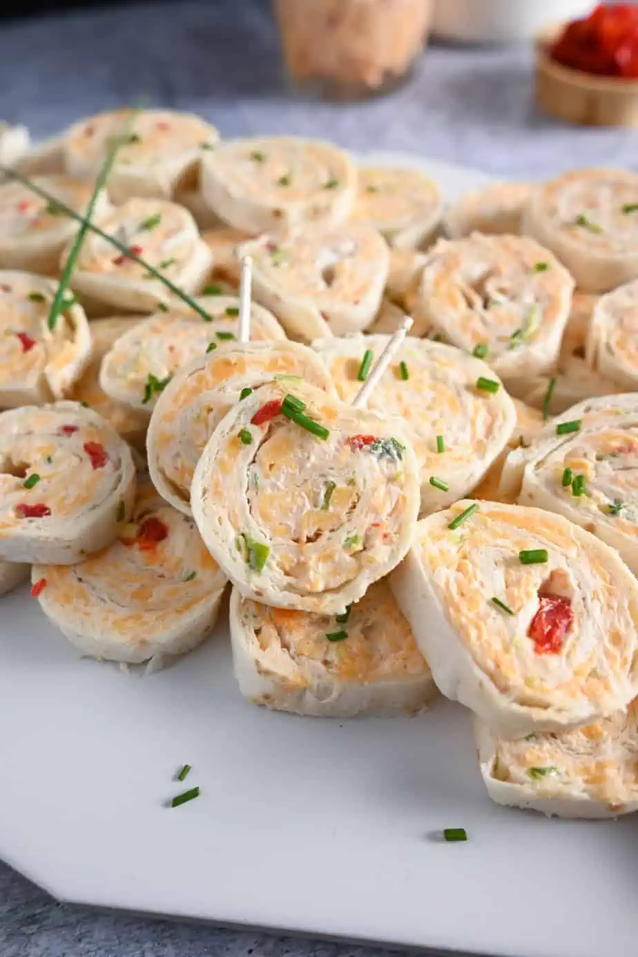 Platter of pimento cheese pinwheels with toothpicks in two of the pinwheels, ready to be taken.