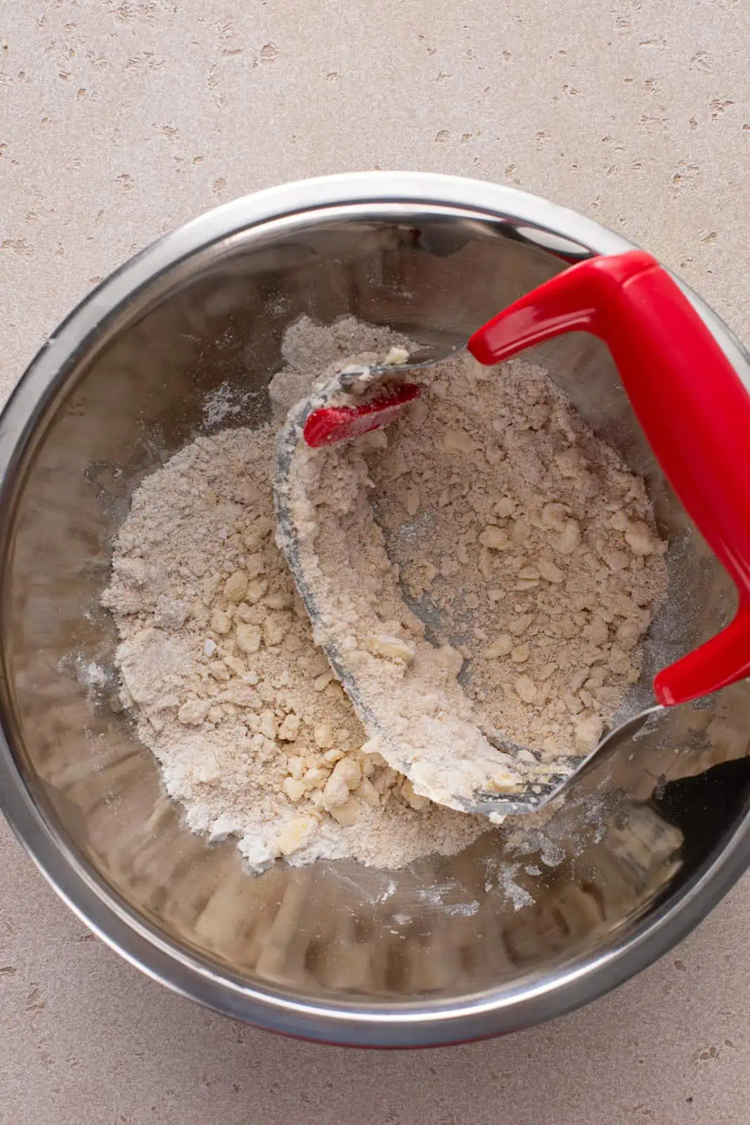 Pastry blender cutting butter into streusel topping ingredients.