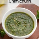 Mint chimichurri in a white bowl set on a wooden board. Text overlay includes recipe name.