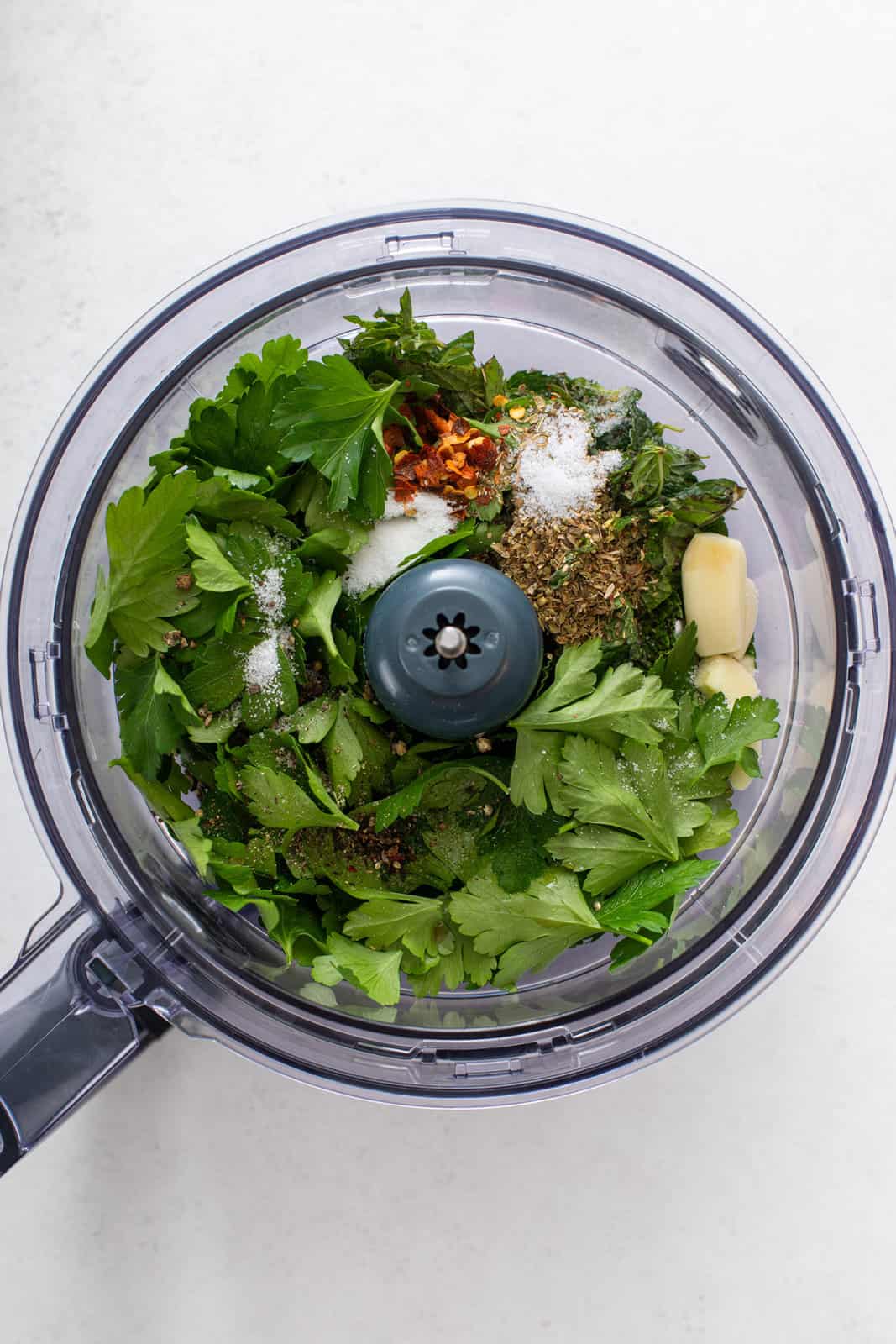 Ingredients for mint chimichurri in the bowl of a food processor.