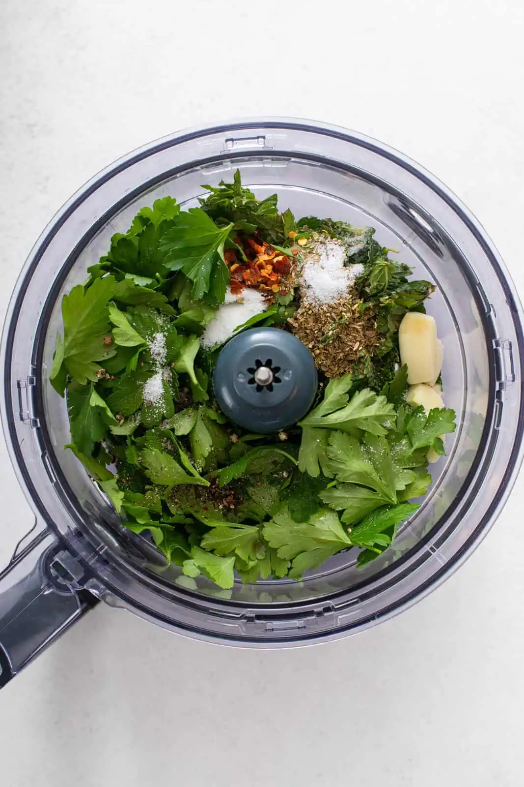Ingredients for mint chimichurri in the bowl of a food processor.