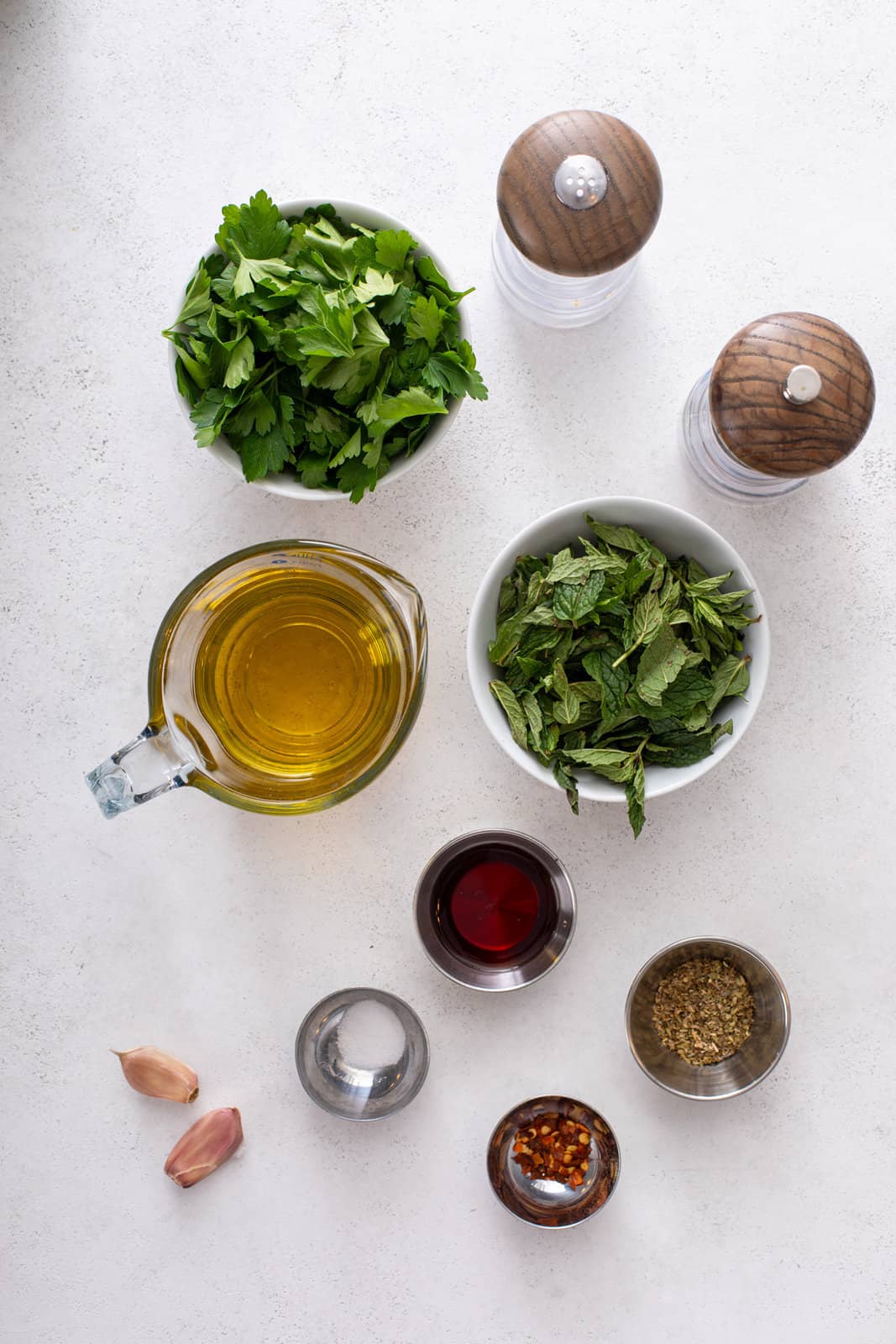 Ingredients for mint chimichurri arranged on a light countertop.