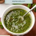 Fresh mint chimichurri in a white bowl with a spoon in it. Text overlay includes recipe name.