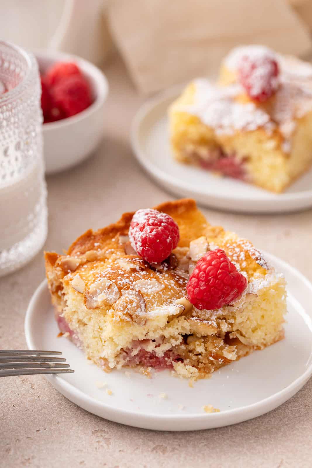 Plated slice of raspberry coffee cake with a bite cut from the corner.