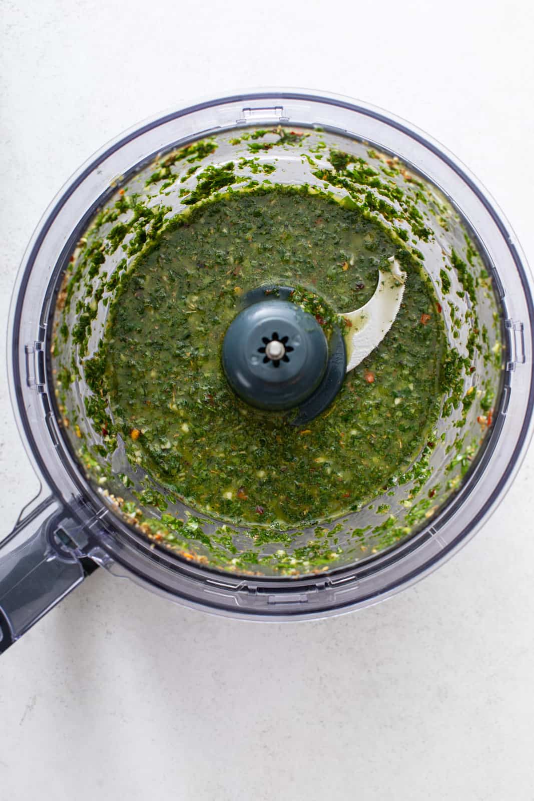 Processed mint chimichurri in the bowl of a food processor.