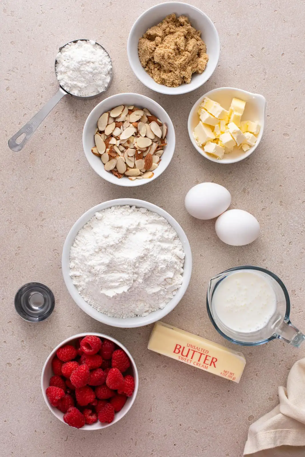 Ingredients for raspberry coffee cake arranged on a beige countertop.