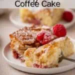 Fork cutting a bite from the corner of a piece of raspberry coffee cake on a white plate. Text overlay includes recipe name.