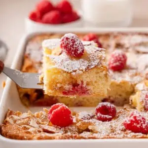 Cake server lifting up a slice of raspberry almond coffee cake.