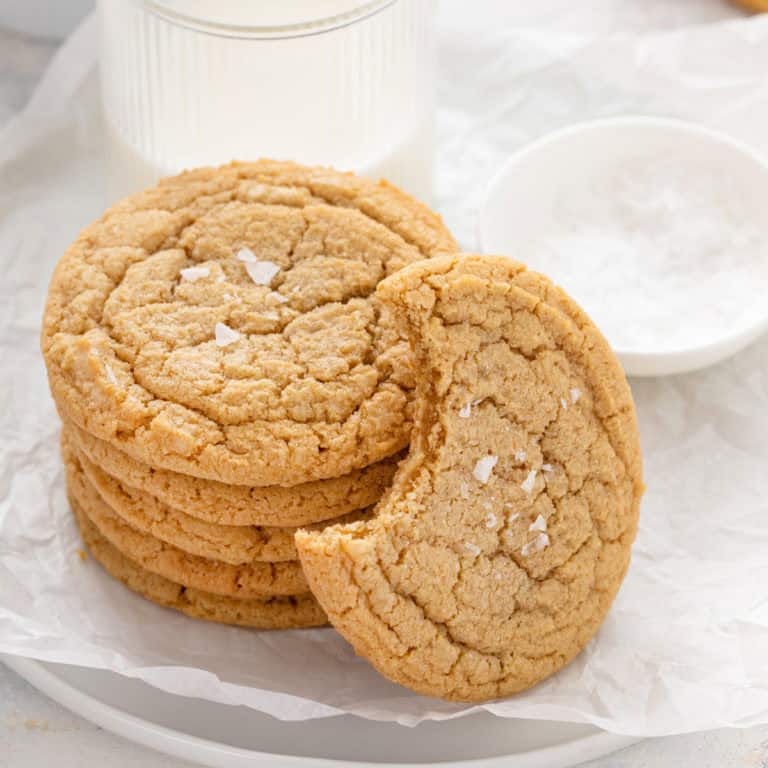 Bite taken from a chocolate chipless cookie leaning against a stack of cookies.