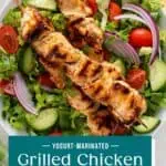 Close up of yogurt-marinated chicken skewers on top of a green salad. Text overlay includes recipe name.