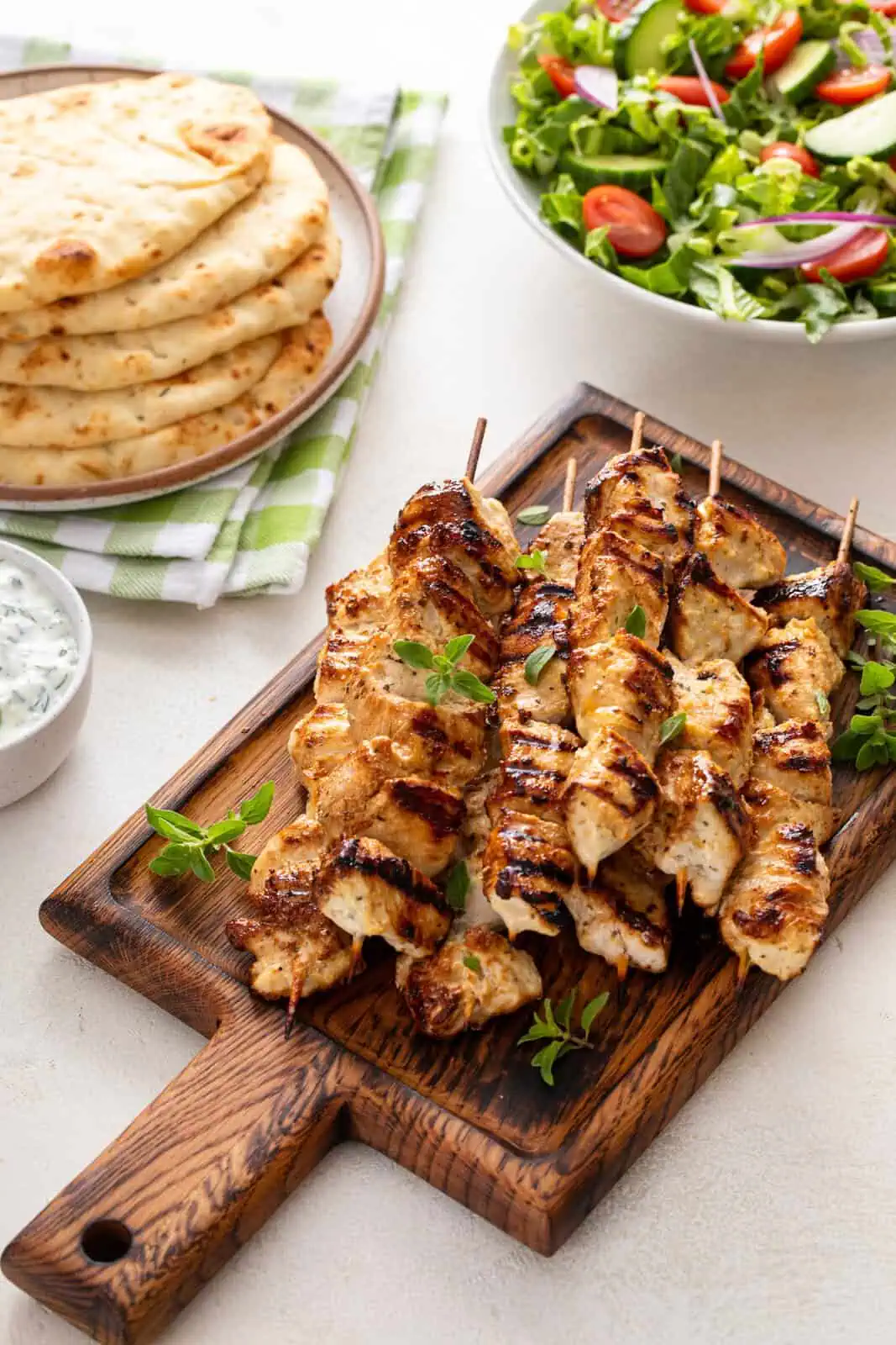 Grilled chicken skewers on a wooden platter.