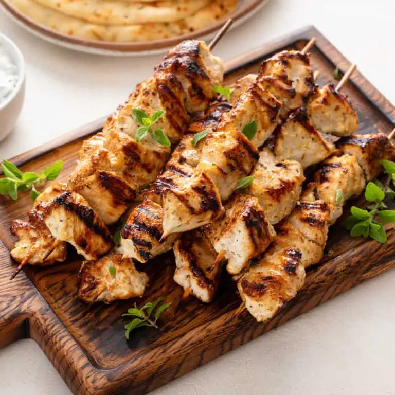 Yogurt-marinated grilled chicken skewers on a wooden platter.