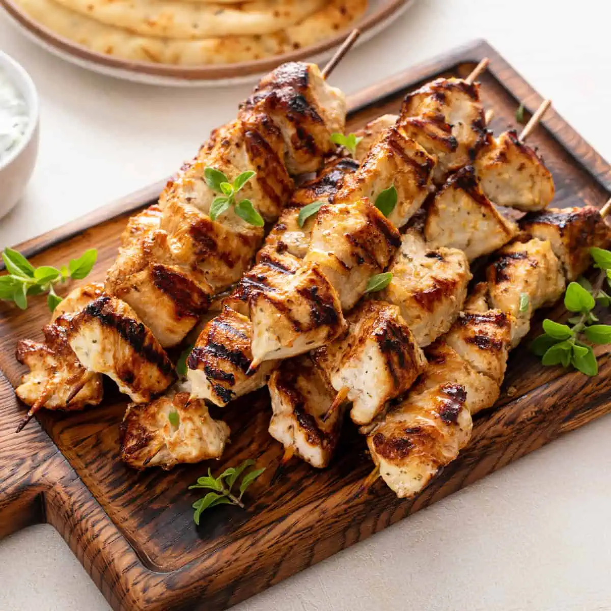 Yogurt-marinated grilled chicken skewers on a wooden platter.