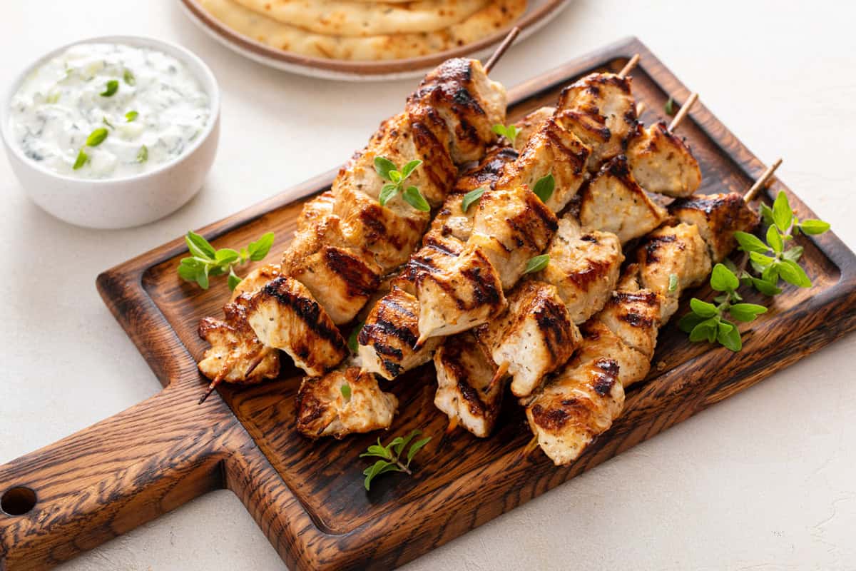 Yogurt-marinated chicken skewers arranged on a wooden board.