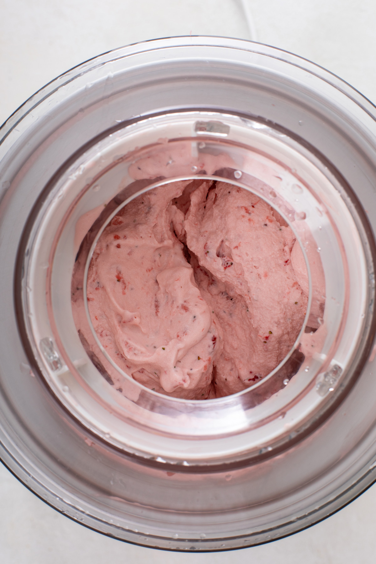 Strawberry ice cream churning in an ice cream maker.
