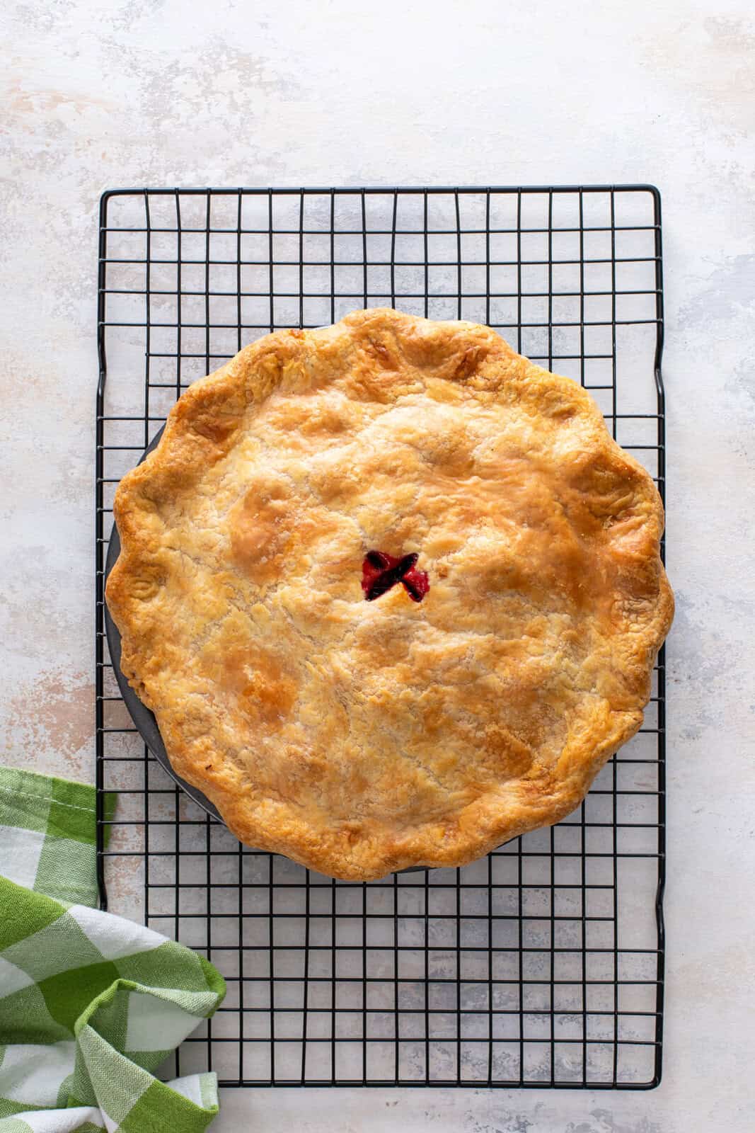 Baked blackberry pie cooling on a wire rack.
