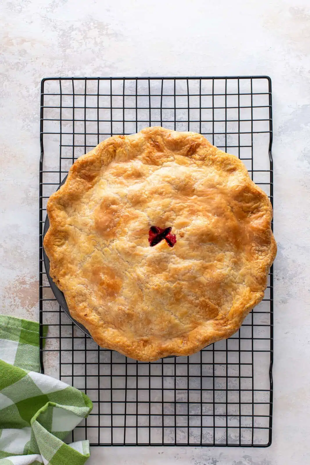 Baked blackberry pie cooling on a wire rack.