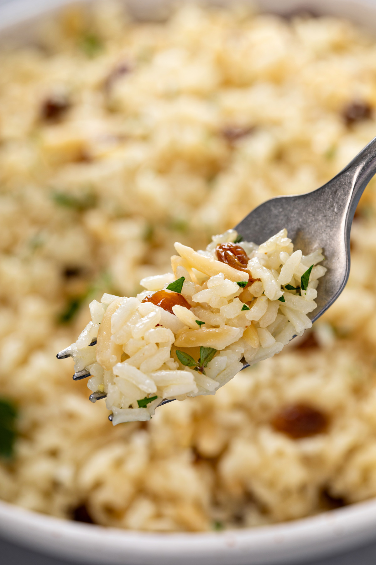 Fork holding up a bite of almond rice pilaf.