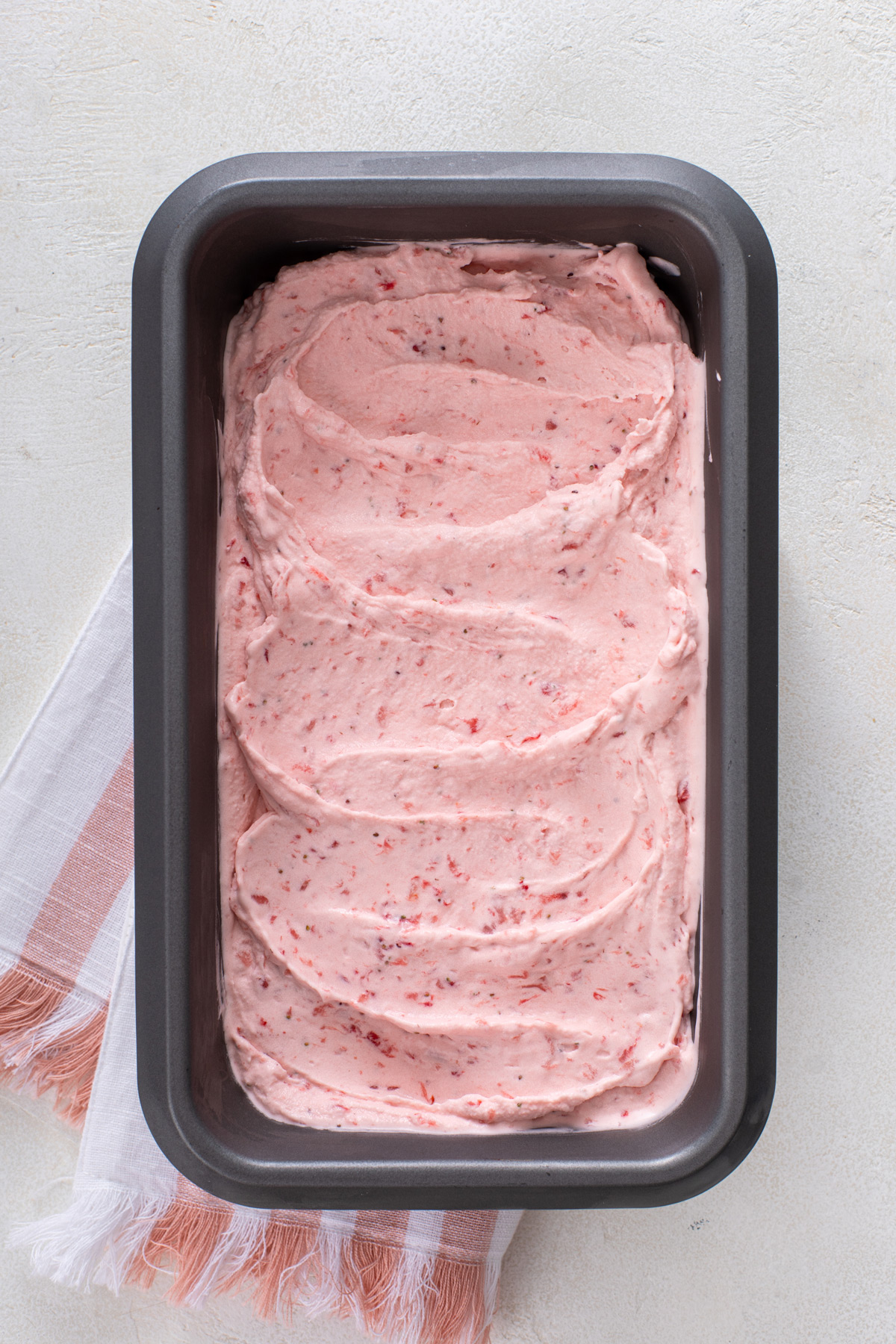 Churned strawberry ice cream in a loaf pan.