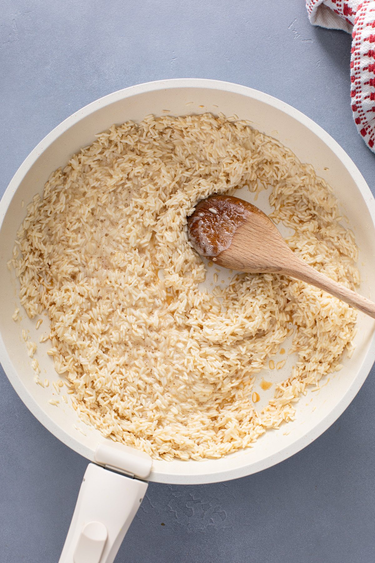 Rice being toasted in butter in a saucepan.