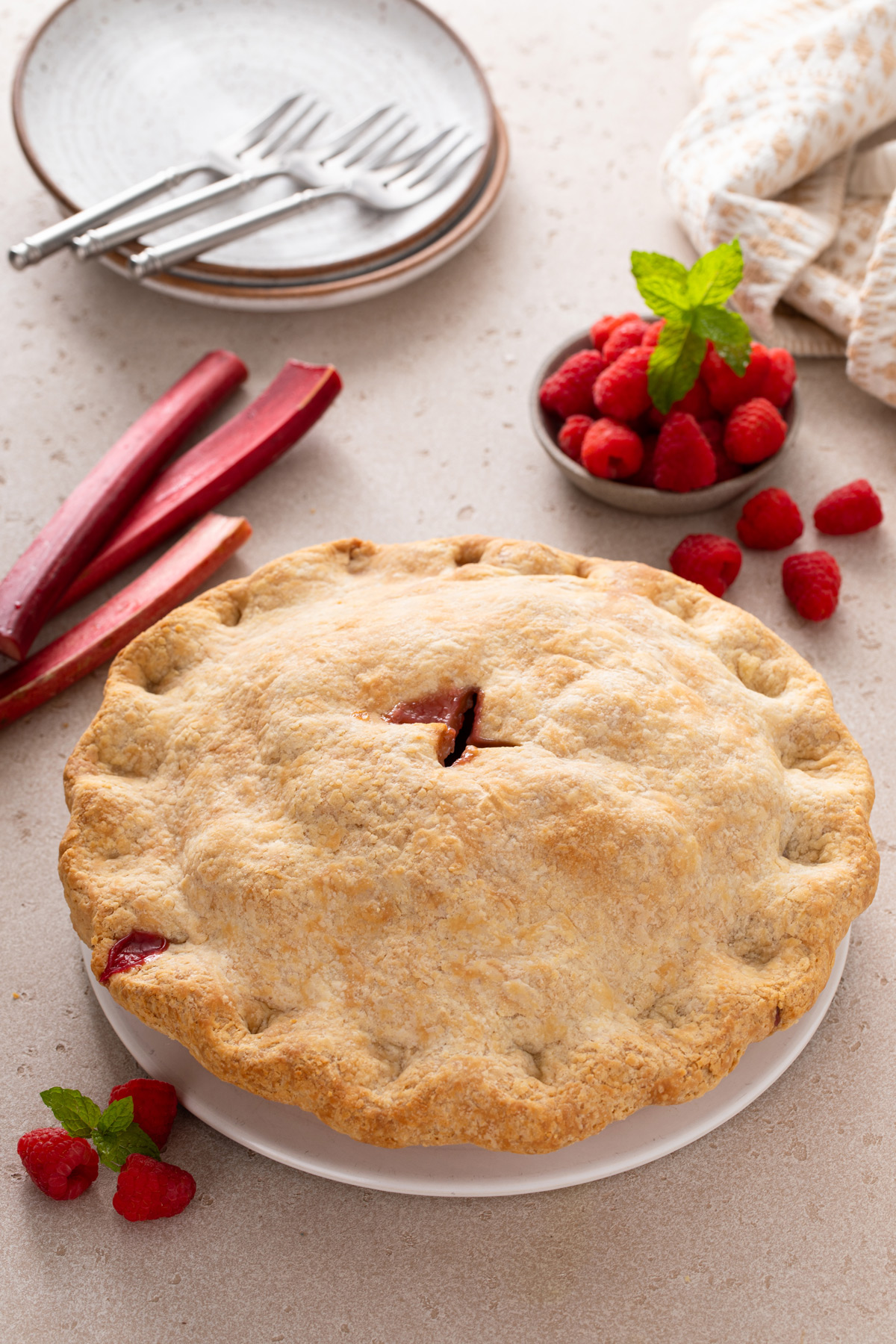 Baked raspberry rhubarb pie on a white plate, ready to be served.