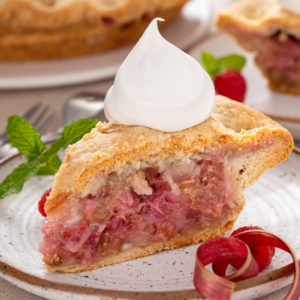 Slice of raspberry rhubarb pie topped with whipped cream.