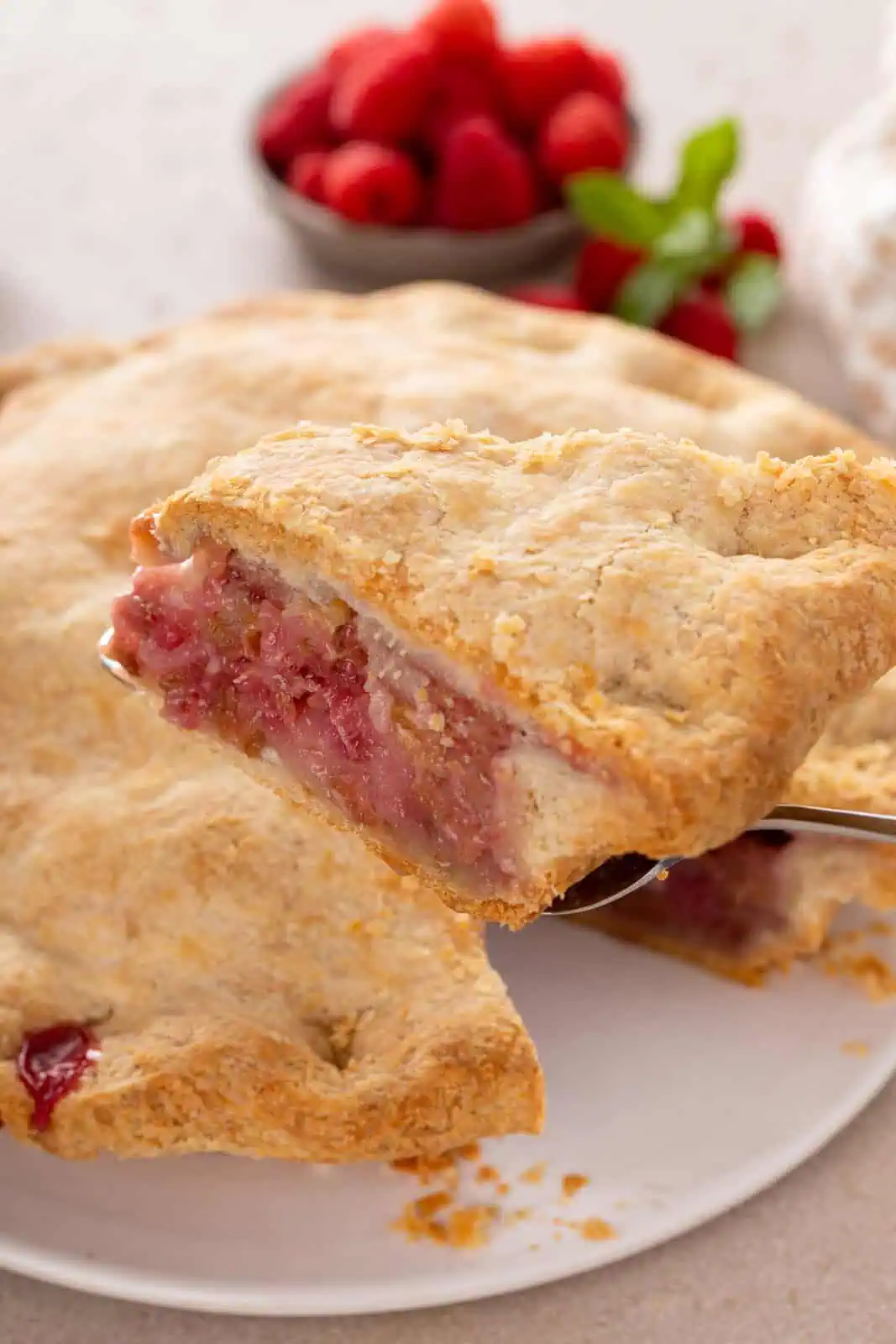 Pie server lifting up a slice of raspberry rhubarb pie.