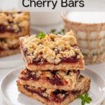 Three sour cherry oat bars stacked on a white plate with a glass of milk in the background. Text overlay includes recipe name.