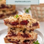 Three cherry bars stacked on a plate with a bite taken from the corner of the top bar. Text overlay includes recipe name.