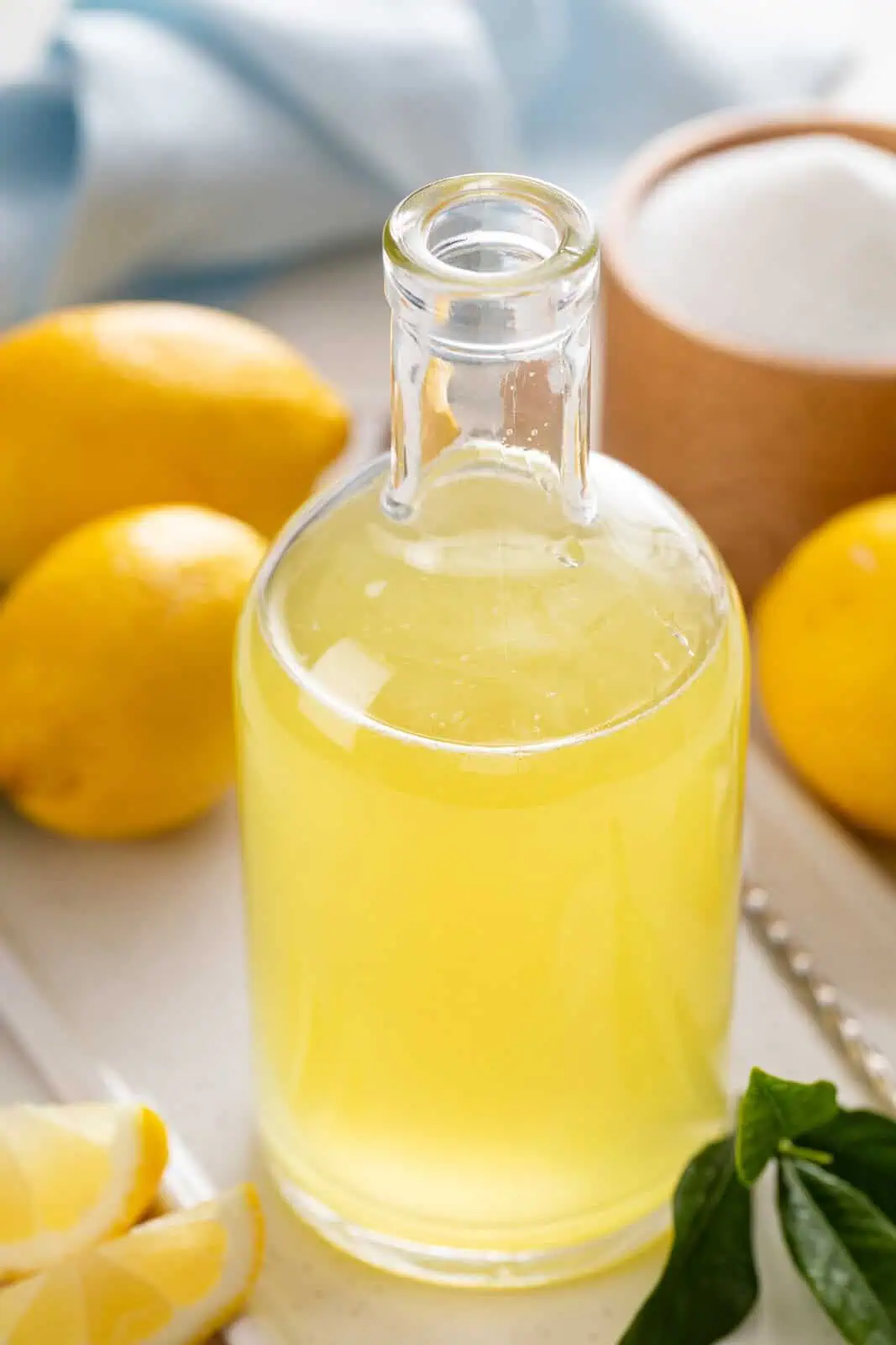 Glass bottle filled with lemon syrup set on a contertop.